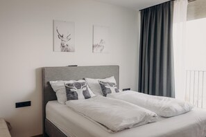 Una cama bien hecha con ropa blanca y dos almohadas, una con un diseño de ciervo.
