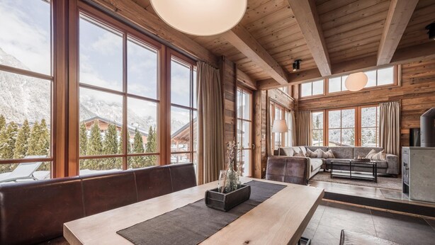 A spacious living area with large windows, a wooden ceiling, and a sofa set. - Superior Chalet Im Weidach (Leutasch)