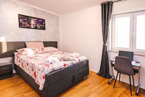 A bedroom with a bed, a desk, a chair, a window with curtains, and a wall-mounted picture. - Ota Residence Koper (Koper)