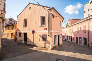 A narrow street with buildings on either side, a no parking sign, and a small shop with a sign in a foreign language. - Ota Residence Koper (Koper)