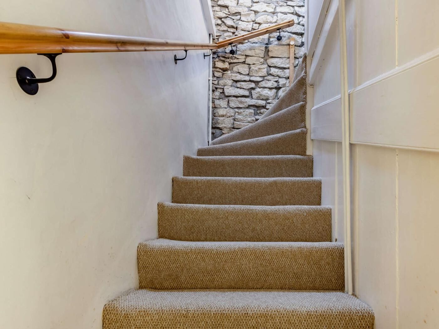 Un escalier dont les marches sont recouvertes de moquette, menant à un mur en pierre.