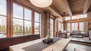 Un intérieur en bois, avec de grandes fenêtres, un coin repas et un salon doté d’un canapé.
