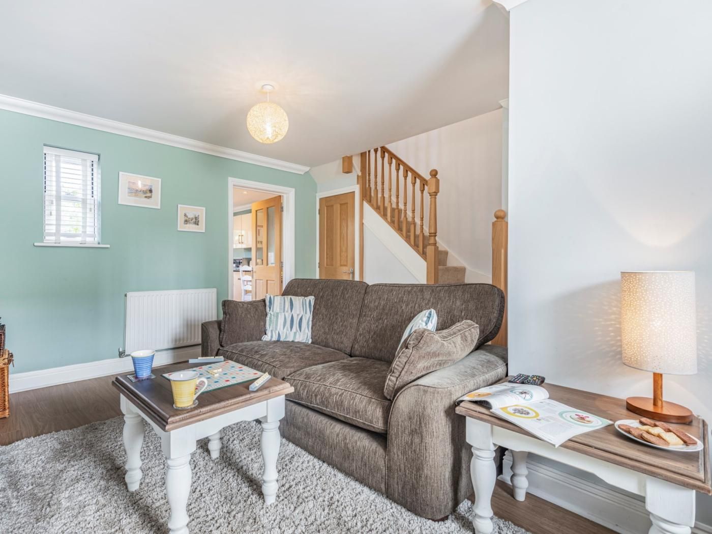 A living room with a sofa, coffee table, and a lamp. There is a staircase leading to another room.