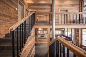 Interior de madera con escalera, balcón y vistas al exterior.