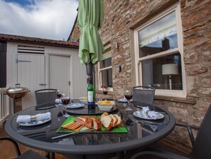 An outdoor dining area with a round table, chairs, a grill, and a bottle of wine. - 2 Bed in Richmond (oc-74284) (Reeth)