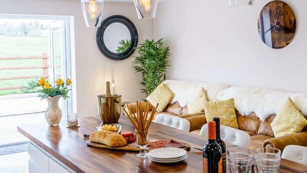 Een eethoek met een houten tafel, een fles wijn, glazen en een plant.
