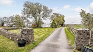 Een landweg naar vakantiehuisjes met stenen muren en een bordje.