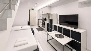 Una habitación de hotel moderna con una cama, un televisor, una pequeña cocina y una escalera.