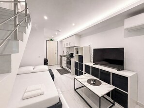 A modern hotel room with a bed, a TV, a small kitchen, and a staircase. - 23 - DIAS Suites by SDR (Paralia)