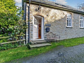 A stone building with a white door and a small porch.
