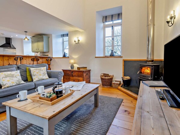 A cozy living room with a sofa, a coffee table, a fireplace, and a television.