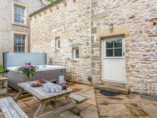 A stone building with a wooden table, hot tub, and outdoor seating area. - 2 Bed in Settle (oc-76649) (Stackhouse)