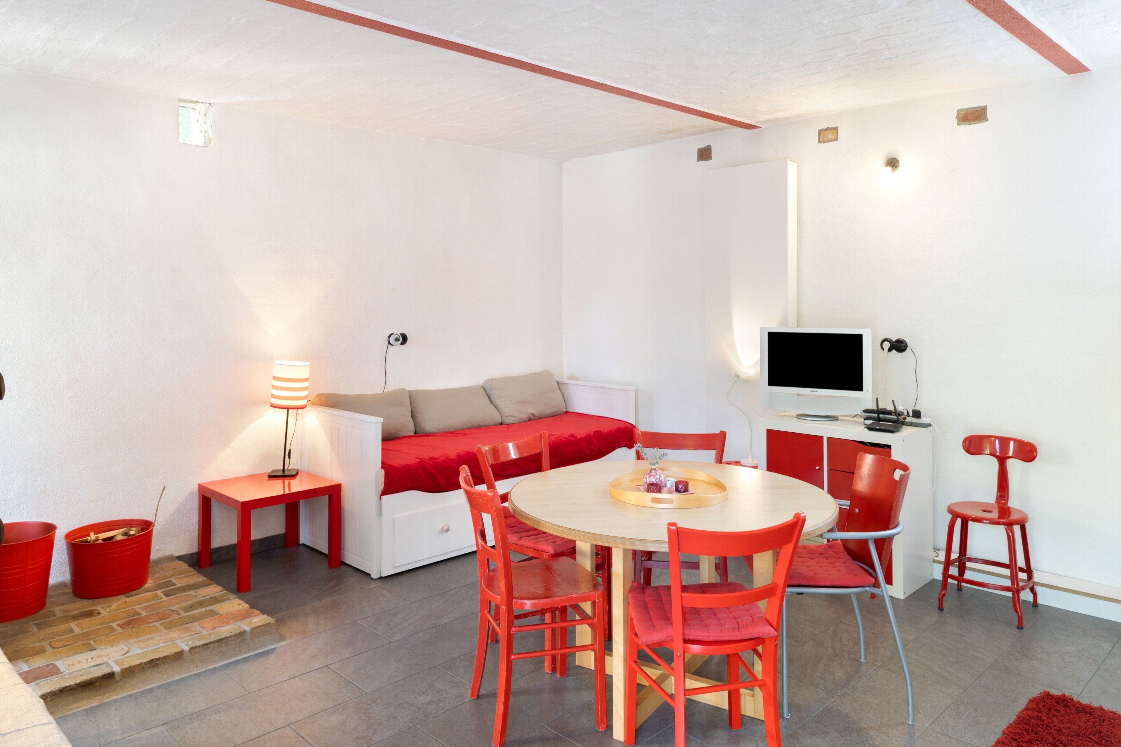 A compact living space with a sofa, a dining table with chairs, a TV, and a lamp.