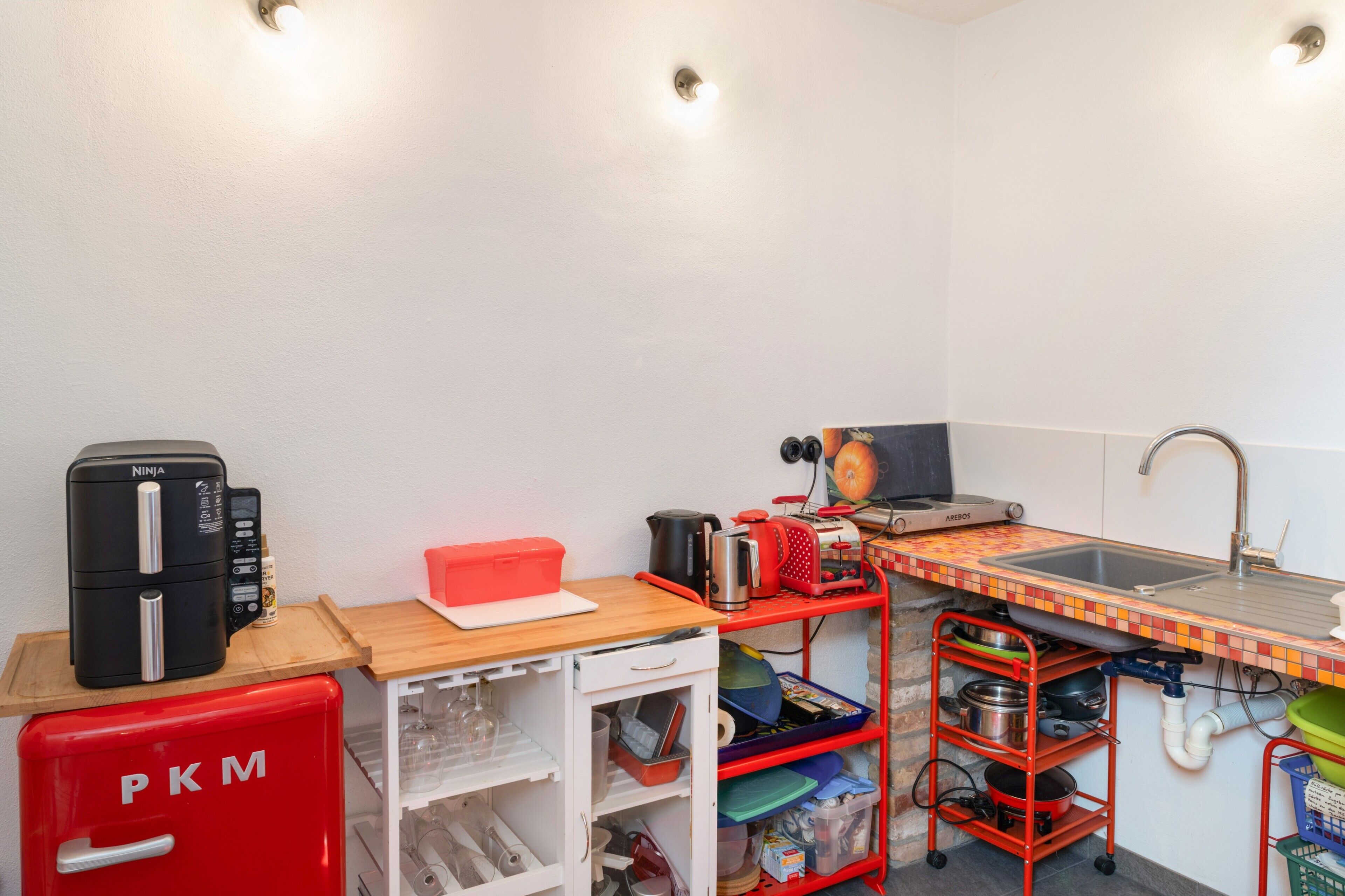 A compact kitchen with a built-in stove, a sink, and a small refrigerator.