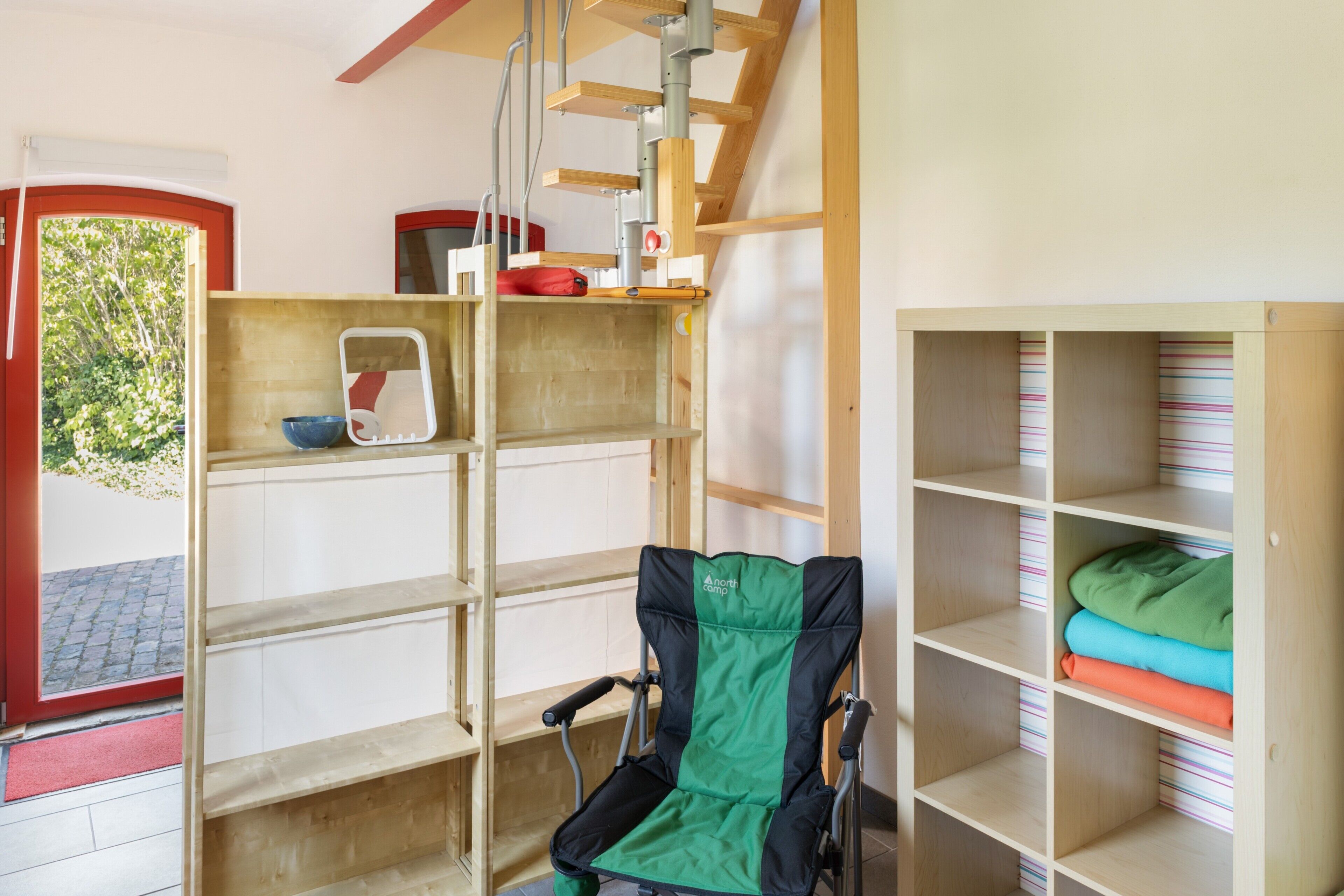 A room with a wheelchair, a shelf with a scale, and a striped storage unit.