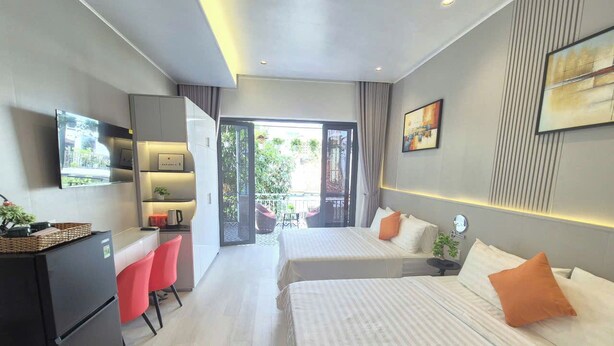 A modern hotel room with a kitchenette, two beds, a dining area, and a balcony with a view. - ApecHotel284 (Ho Chi Minh City)