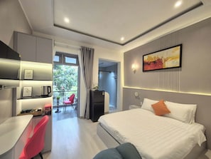 Una camera d'albergo moderna con un letto, una scrivania, una sedia, un angolo cottura e vista sull'esterno.