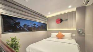 A modern hotel room with a large bed, a small bedside table, a wall-mounted clock, and a window with a view. - ApecHotel284 (Ho Chi Minh City)