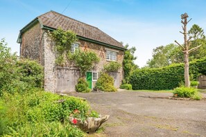 A stone house with a green door, a garage, and a driveway.