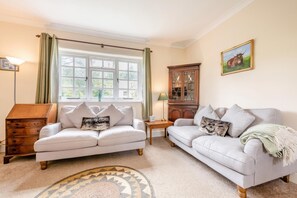 A room with two sofas, a wooden cabinet, a lamp, and a painting on the wall.