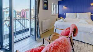 Ein Hotelzimmer mit Bett, einem Sessel, Blick ins Freie und einem fenster mit Vorhängen.
