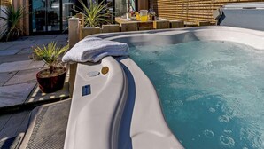 Ein Whirlpool mit Holzterrasse, einem Blumentopf und einem Handtuch am Rand.