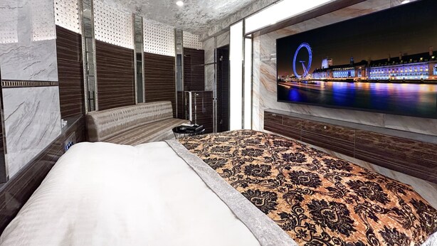 A modern hotel room with a large bed, a television displaying a cityscape, and a view of a Ferris wheel. - hotel CenturyANNEX (Chiba)