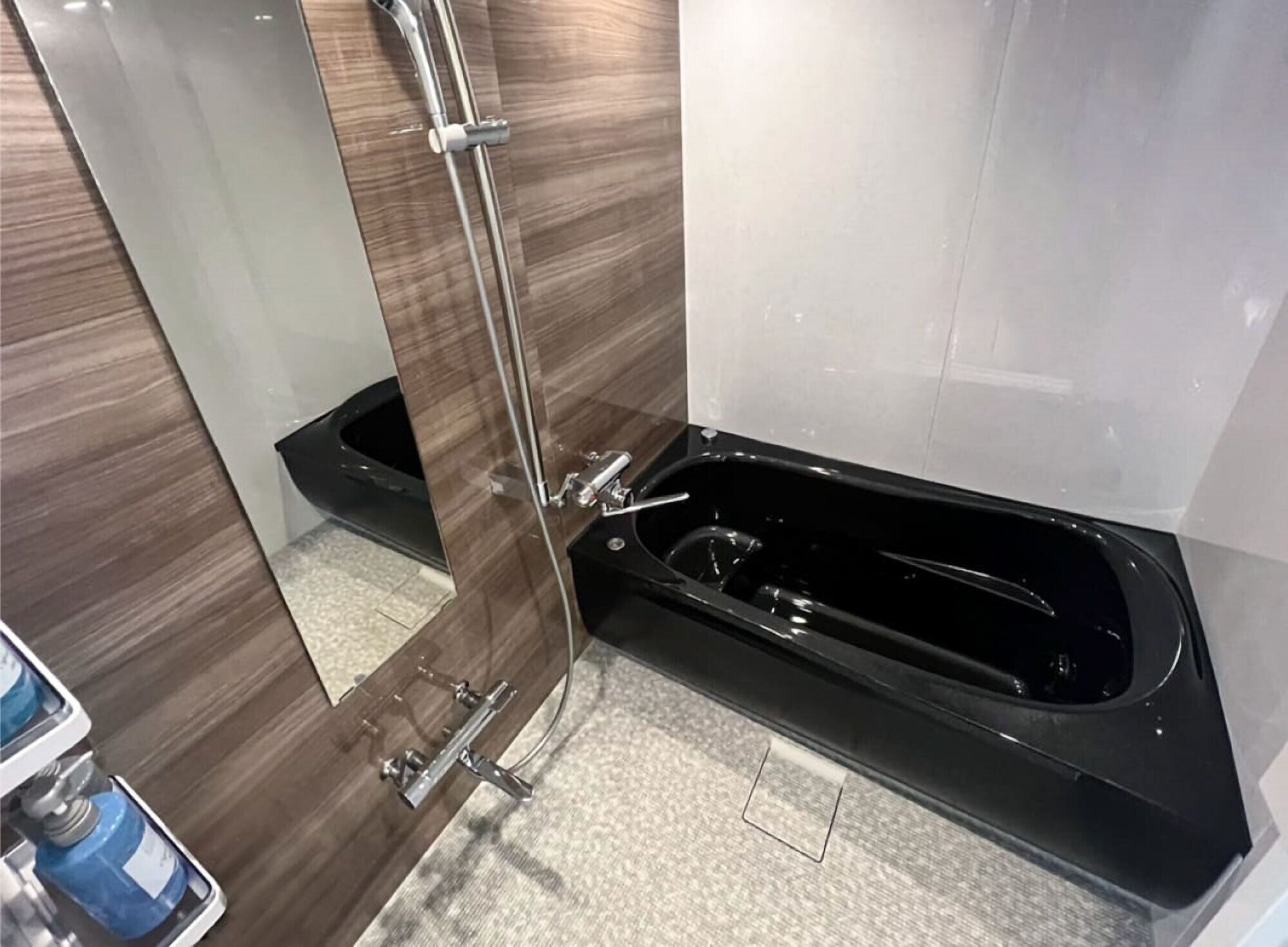 A bathroom with a glass shower enclosure, a black bathtub, and a tiled floor.