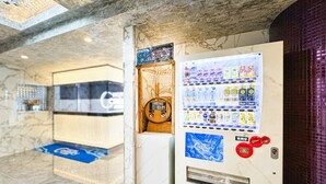 A hotel lobby with a marble floor, a vending machine with beverages, and a blue carpet. - hotel CenturyANNEX (Chiba)