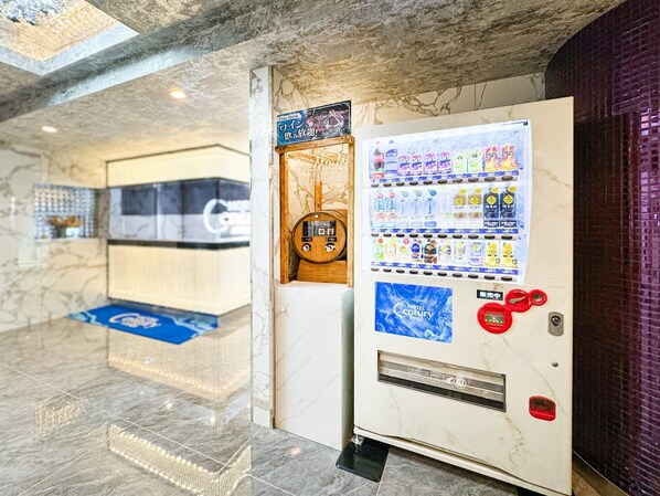 A hotel lobby with a marble floor, a vending machine with beverages, and a blue carpet. - hotel CenturyANNEX (Chiba)