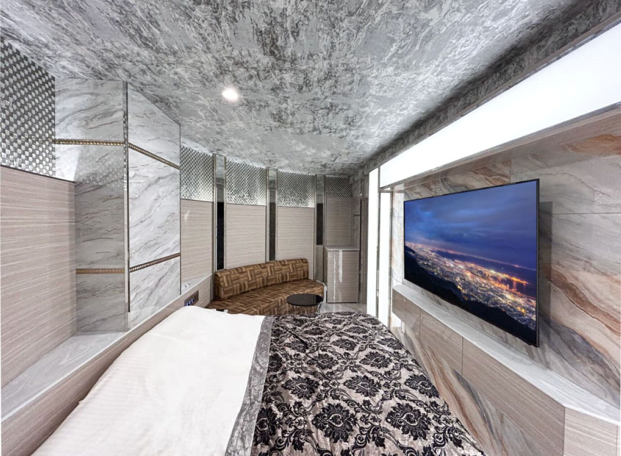 Un dormitorio con una cama grande, un televisor en la pared y una alfombra estampada.