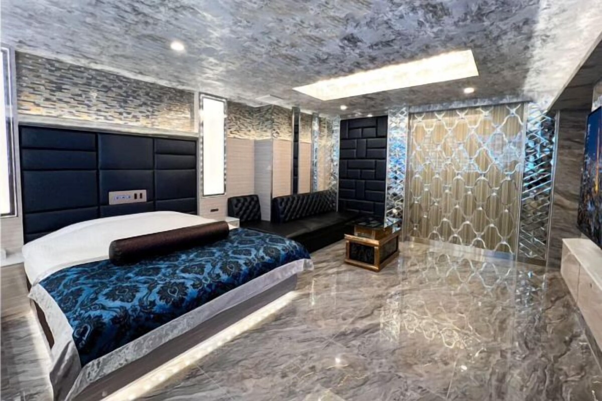 A modern bedroom with a large bed, a seating area, and a decorative wall.