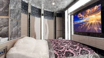 A modern bedroom with a bed, a large TV, and a view of the sky.
