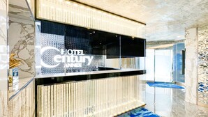 A modern hotel reception area with a digital display and a blue carpet with the hotel name. - hotel CenturyANNEX (Chiba)