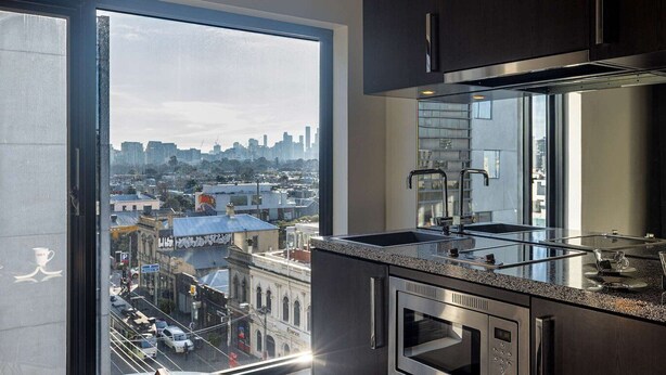 Una cocina moderna con un amplio ventanal, electrodomésticos de acero inoxidable y vista a la ciudad.