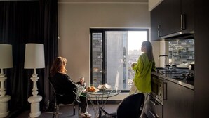 Cocina moderna con un ventanal grande, zona de comedor con mesa de vidrio y vista a la ciudad.