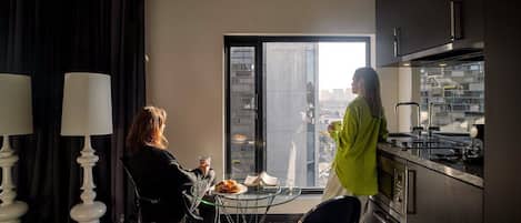 Cocina moderna con un ventanal grande, zona de comedor con mesa de vidrio y vista a la ciudad.