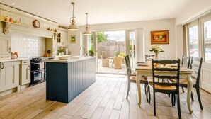 Una cocina con una isla central, un comedor con mesa y sillas, y vistas al exterior.