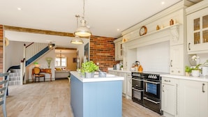 Una cocina amplia con una isla central, armarios blancos y una pared de ladrillo decorativa.