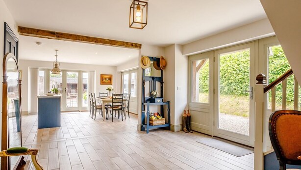 Un amplio espacio habitable con piso de madera, una mesa de comedor y una cocina visible a través de una puerta abierta.