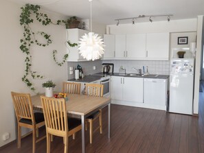 A modern kitchen with white cabinets, a wooden dining table, and chairs. - Seaview apartment in Henningsvær (Vågan)