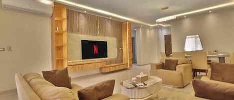 Una sala de estar moderna con televisor de pantalla plana, sofás cómodos, una mesa de centro y una estantería empotrada.