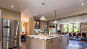 Een moderne keuken met een centraal eiland, roestvrijstalen apparatuur en een eethoek met uitzicht.