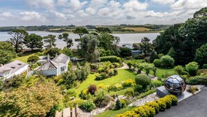 Een woonhuis met een verzorgde tuin, een bolvormige buitenstructuur en uitzicht op een meer.