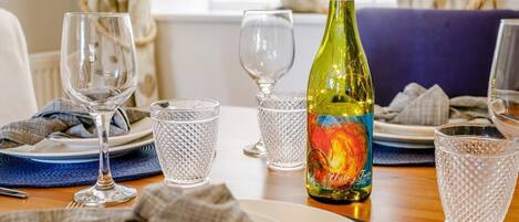 A dining table set with plates, glasses, and a bottle of wine.
