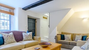 A living room with two sofas, a wooden coffee table, and a staircase leading to an upper level. - 3 Bed in Matlock (oc-78591) (Cromford)