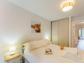 A bedroom with a bed, a bedside table with a lamp, a painting, and a view of the outside. - 2 Bed in Brockenhurst (oc-78728) (Brockenhurst)