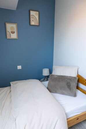A bedroom with a bed, a nightstand, a lamp, and two wall art pieces. - Cozy duplex for 4 people with a garden (Bischoffsheim)
