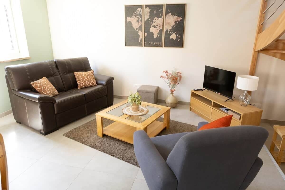 Un salon avec un canapé, une table basse, un téléviseur et une carte du monde accrochée au mur.