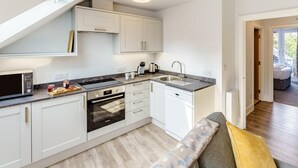 Een moderne keuken met witte kasten, een inbouwoven, een koffiezetapparaat en een spoelbak.